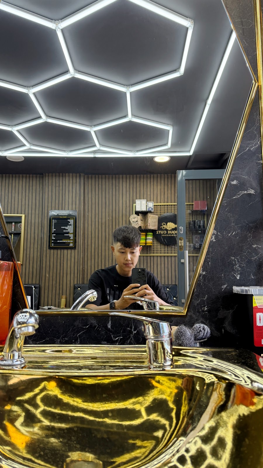 Inside Unique Cutz: hexagon LED ceiling lights, wood-slat walls and a barber at the gold reception counter