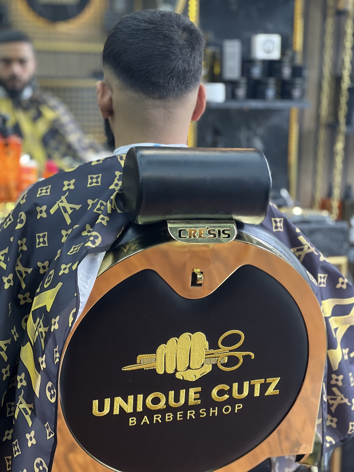 Crisp taper fade seen from behind, client seated in the chair
